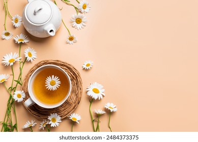 Chamomile tea in cup and teapot and chamomile buds on beige background, top view. Healthy herbal drinks and daisy flowers, trendy eco lifestyle concept. - Powered by Shutterstock