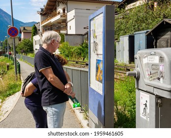 Chamonix, France - Aug 13, 2017: Senior Couple Reading On The Public Tourist Map Their Location In Chamonix Near The Railway Track With Cottages In The Background