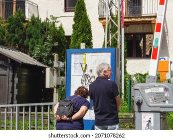 Chamonix, France - Aug 13, 2017: Rear View Of Senior Couple Reading On The Public Tourist Map Their Location In Chamonix Near The Railway Track With Cottages In The Background