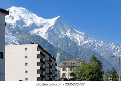 Chamonix village aerial at the feet of the Mont Blanc Massive mountain range with eternal snow tops in the background during summer. Tourist destination and outdoor winter sports  ski resort.