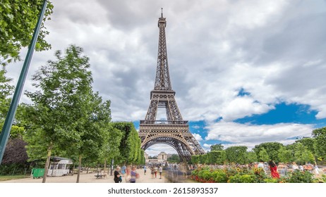 Champ de Mars and the Eiffel Tower timelapse hyperlapse in a sunny summer day. Paris, France. Green trees and cloudy sky, people walking around. Motion toward