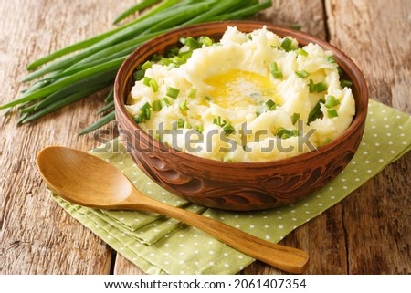 Champ is an Irish dish Mashed potatoes with green onions close up in the bowl on the table. Horizontal
