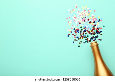 Champagne Bottle With Colorful Confetti On Mint Background