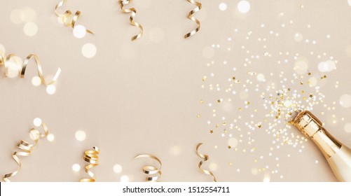 Champagne Bottle With Confetti Stars, Bokeh Decoration And Party Streamers On Golden Background. Christmas, Birthday Or Wedding Concept. Flat Lay.