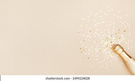 Champagne Bottle With Confetti Stars On Golden Festive Background. Christmas, Birthday Or Wedding Concept. Flat Lay.