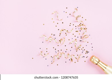 Champagneflaska med konfettistjärnor och feststreamers på rosa bakgrund. Jul, födelsedag eller bröllop koncept. Platta lay-stil. Stockfoto