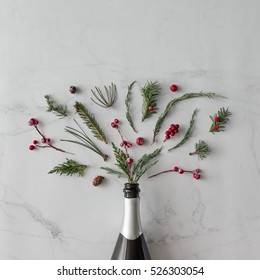 Champagne Bottle With Winter Foliage On Marble Background. Flat Lay. Party Concept.