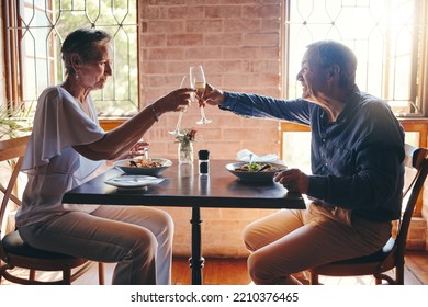 Champagne, Celebration And Senior Couple Giving Toast For Love, Anniversary Or Birthday With Lunch At A Restaurant. Elderly Man And Woman Giving Cheers With Wine To Celebrate Marriage At A Cafe