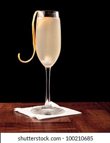 Champagne Cocktail Served On A Bar Top Isolated On Black Garnished With An Orange Twist