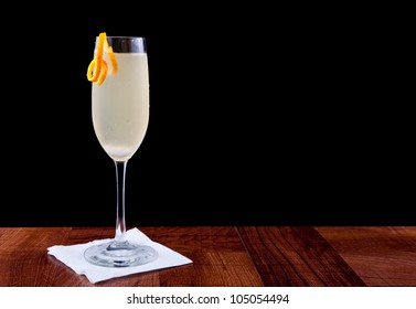 Champagne Cocktail Served On A Bar Top Isolated On Black Garnished With An Orange Twist