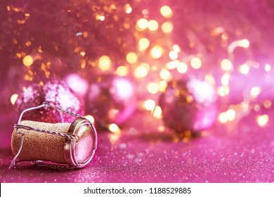 champagne cork and pink shiny christmas balls on glittering abstract background. christmas and new year holiday concept. symbol of festive winter season. close up