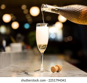 Champagne flute pouring sparkling wine with Christmas lights in the background, holiday season, New Years celebration - Powered by Shutterstock