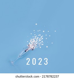 Champagne glass on blue background glass surrounded by silver star confetti and numbers 2023 . New Year celebration or party concept. Selective focus, copy space - Powered by Shutterstock