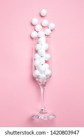 Champagne glass with white balls on pink background minimal style.