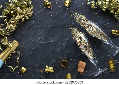 Champagne glasses with colorful glitter confetti with bottle of sparkling wine, celebrate flat lay