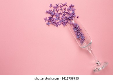 Champagne Glasses With Lilac Flowers On Pink Color Paper Background Minimal Style.Summer Holiday.