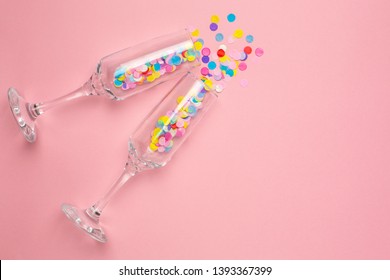 Champagne Glasses With Multi-colored Confetti On Pink Color Paper Background Minimal Style. Flat Lay Composition For Birthday, Mother Day Or Wedding