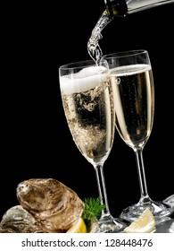 Champagne glasses with oysters and champagne pouring
