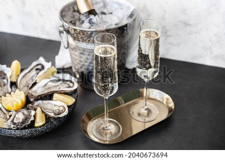Champagne glasses with sparkling wine and bottle in bucket near oysters