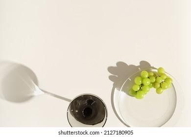 Champagne Glasses Tinted Grey Glass And Grape On Beige Background With Dark Shadows From Sun. Minimal Summer Cold Drinks Concept. Trend Wine Glass, Colored Glassware. Creative Top View, Pale Colors 