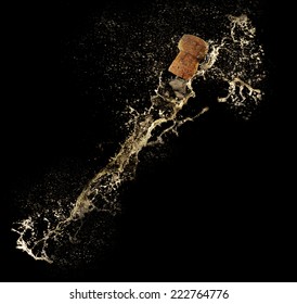 Champagne splashes with cork on black background