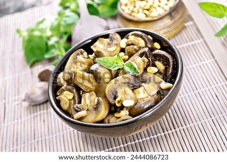 Champignons baked with oregano, wine, garlic, lemon and pine nuts in bowl on background of brown bamboo napkin