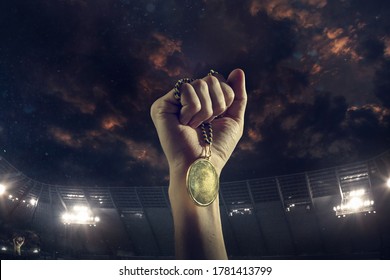 Champion. Award of victory, male hands tightening the golden medal of winners against cloudy dark sky. Sport, competition, championship, winning, achieving the goal. Prize for success and honor.