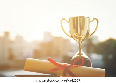 Champion golden trophy with Graduation certificate on city sunset time with copy space. Success and Education concept. - Powered by Shutterstock