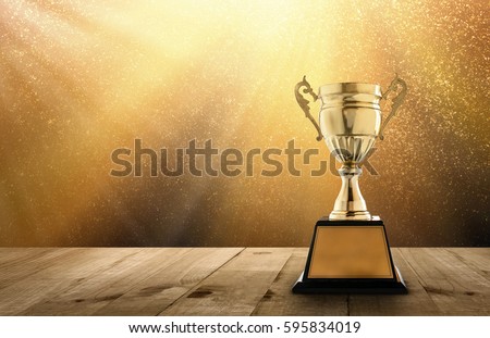 champion golden trophy on wood table with copy space and gold Twinkly Lights and glitter stars light background copy space ready for your design.