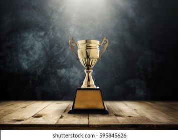 champion golden trophy placed on wooden table with dark background copy space ready for your design win concept.
