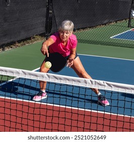 Champion pick;eball player bends low to hit a backhand volley - Powered by Shutterstock