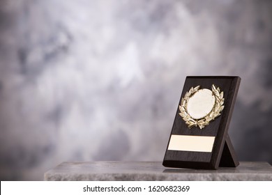 Champion  Trophy Plaque Placed On Marble Table With Gray Background Copy Space Ready For Your Winning Design Concept.