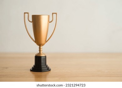 Champion victory golden trophy toy model on wooden with white wall background copy space. Concept of champion, winner, top, successful competition in business, financial, marketing, investment, sport.