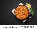 Chana Masala or Chole in black bowl on dark slate table top. Indian cuisine veg chickpeas curry dish. Asian spicy vegetarian food and meal. Copy space. Top view