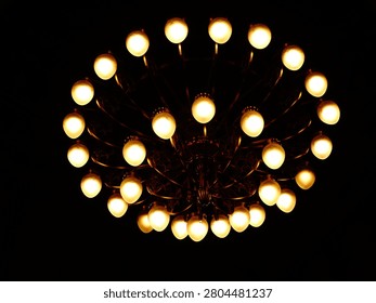 Chandelier with multiple glowing light bulbs creating warm light in darkness