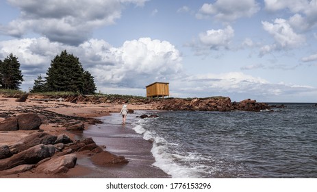 Chandler, Canada - August 13 2020 : Woman Walking Along The Beach In Gaspé Peninsula 