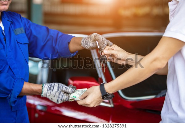 Change Car keys in hand and cash in the\
hands of charging money to repair cars in garage\
