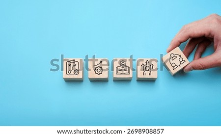 Change management process concept with hand arranging wooden blocks showing strategy, growth, learning, leadership, and teamwork icons, symbolizing organizational transformation, business improvement