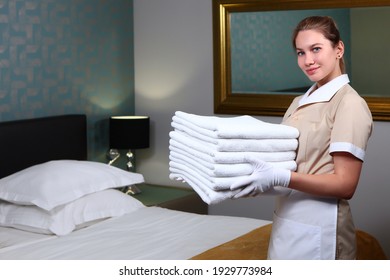 Change Of Towels In The Hotel Room. A Uniformed Maid Cleans The Room. Friendly Hotel Staff. Concept Of The Hotel Business. Photos In The Interior.