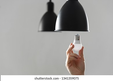 Changing The Bulb For Led Bulb In Floor Lamp In Black Colour. On Light Gray Background.