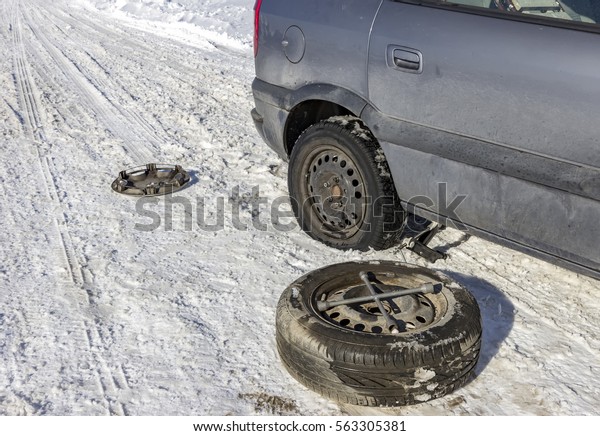 changing a
flat tire in the winter snow with
backup