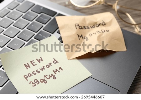 Changing password. Notes with new and old passwords, laptop and glasses on wooden table, closeup