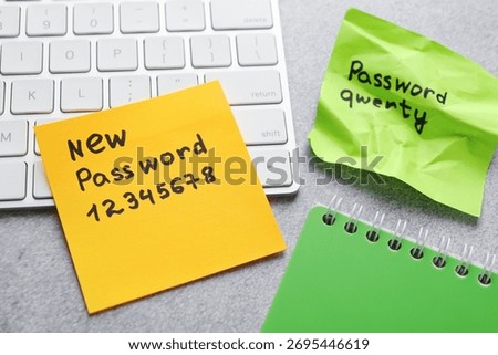 Changing password. Sticky notes with old and new passcodes, computer keyboard and notebook on grey table, above view