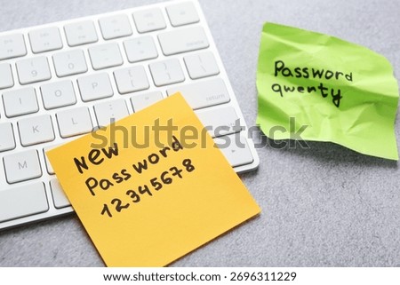 Changing password. Sticky notes with old and new passcodes near computer keyboard on grey table, closeup