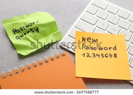 Changing password. Sticky notes with old and new passcodes, computer keyboard and notebook on grey table, closeup