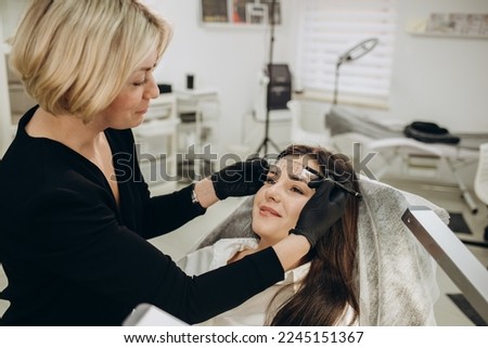 Changing the shape of the brows. Stylist measuring the eyebrows with the ruler. Micropigmentation work flow in a beauty salon. Woman having her eye brows tinted with Semi-permanent makeup.
