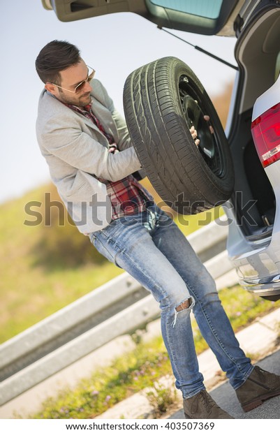 Changing tire on broken car on\
road