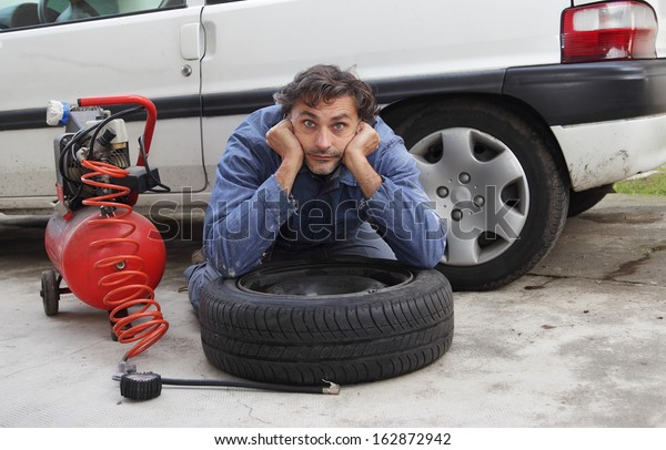 Changing a tire,\
pensive man and spare\
wheel