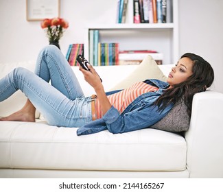 Channel Surfing. Shot Of A Young Woman Watching Television At Home.