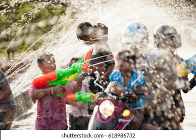 Chanthaburi (Thailand) - Apr 12, 2012. Children enjoy using plastic water guns splashing water on people passing them in the street with artificial water tunnel during Songkran Water Festival.